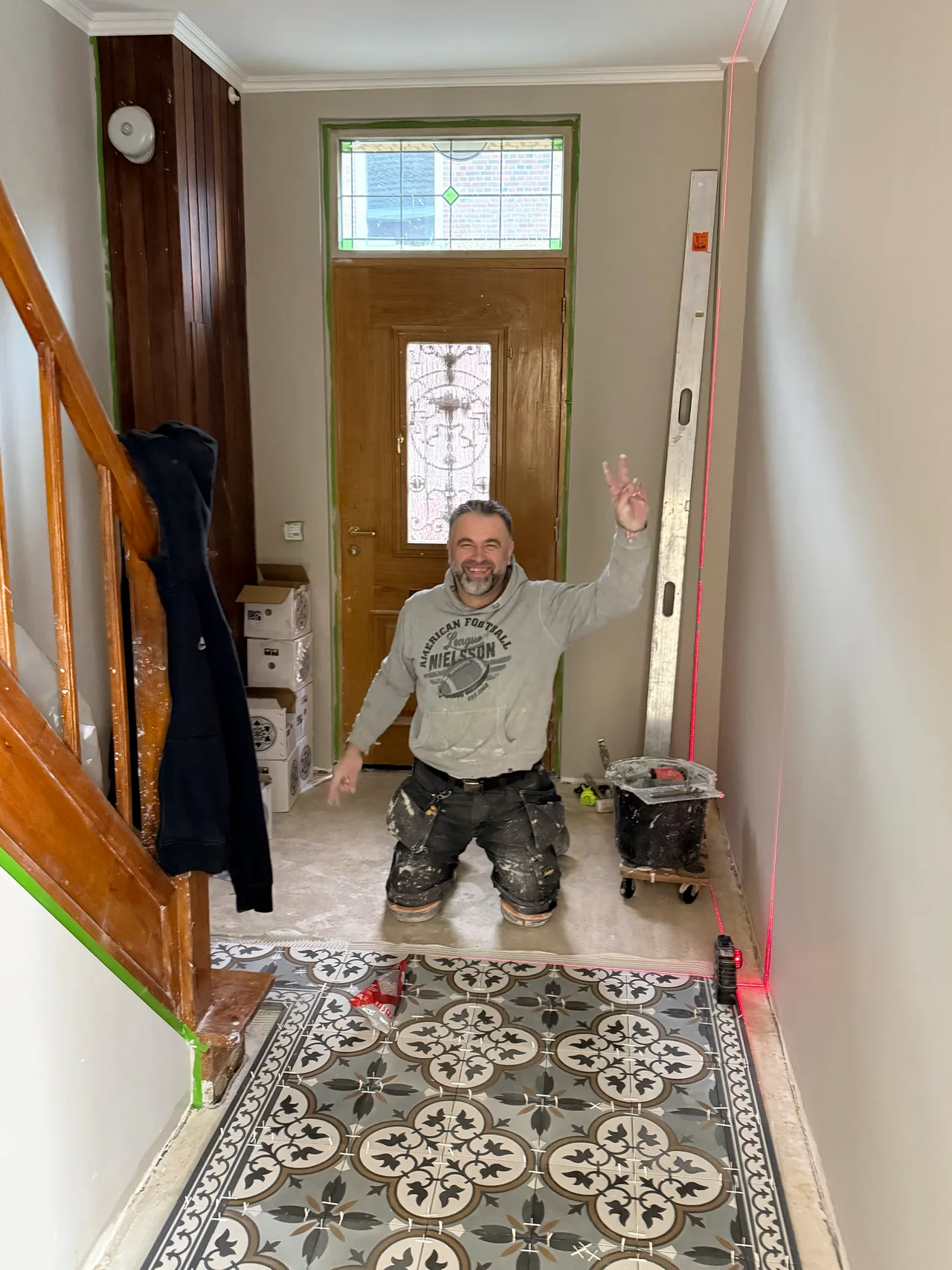 Almir Hukic, lachend op de werkplek tijdens het leggen van een tegelvloer